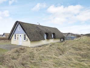A thatched-roof house with a single entrance and a small porch area.