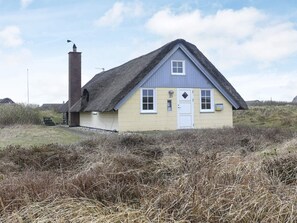 A single-story house with a thatched roof, a chimney, and a small porch.