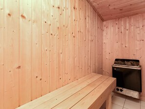 Un sauna de madera con banco y equipo.