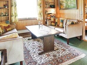A cozy living room with a sofa, armchairs, a coffee table, and a patterned rug.