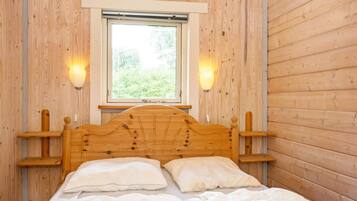 A wooden-framed bed with two pillows and a window above it.
