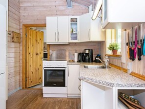 A compact kitchen with wooden walls, a stove, a sink, and cabinets. - Pleasant Holiday Home in Silkeborg near Lake (Silkeborg)