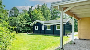 A small, dark green wooden building with a covered porch and a gravel path leading to it. - Pleasant Holiday Home in Silkeborg near Lake (Silkeborg)