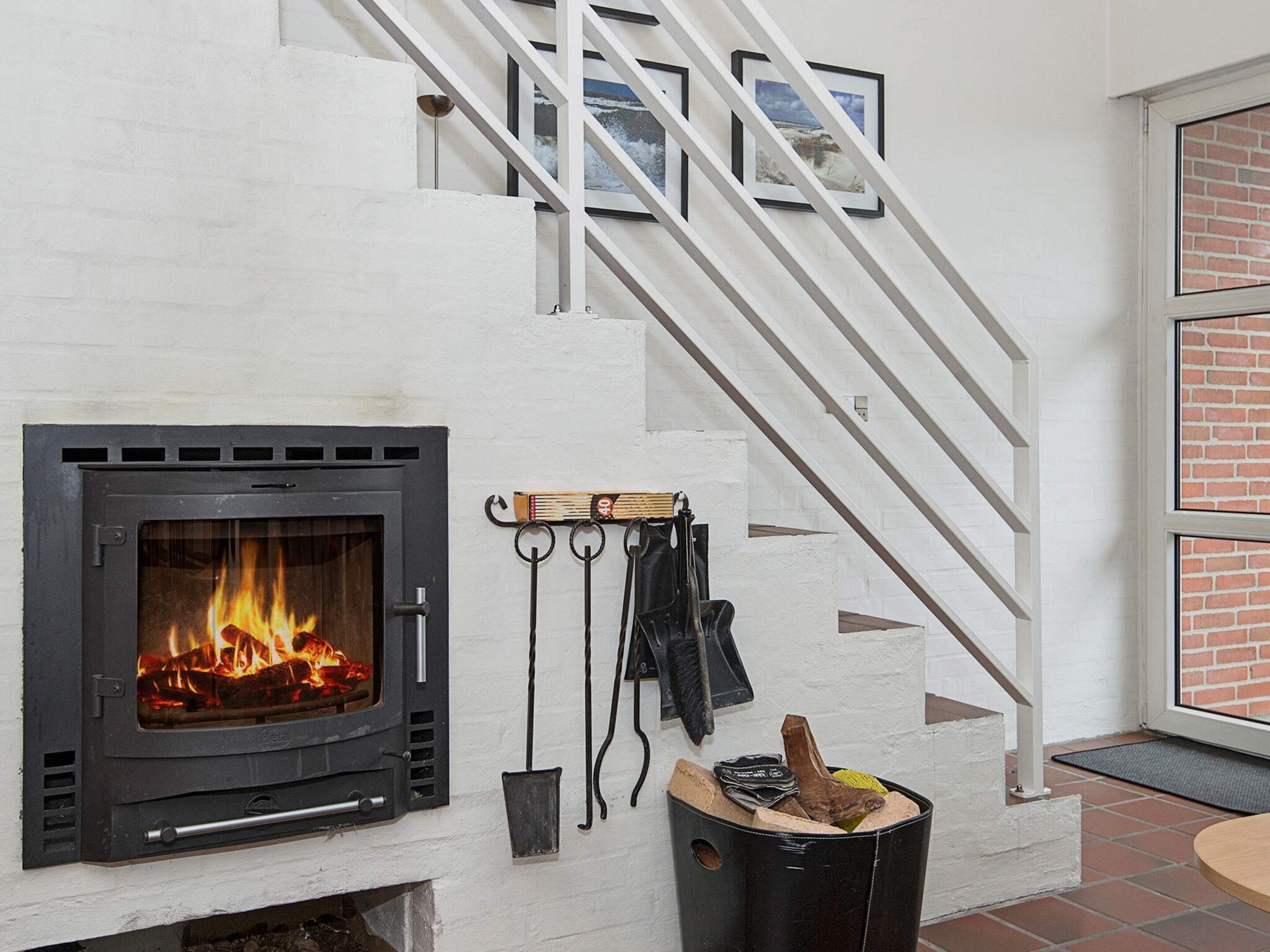 A modern interior with a fireplace, a staircase, and a door leading outside.