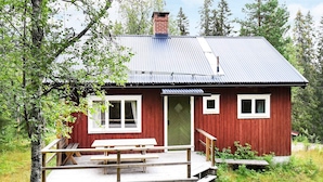 A red wooden cabin with a metal roof, a wooden deck, and a door. - 8 Person Holiday Home in Salen (Salen)