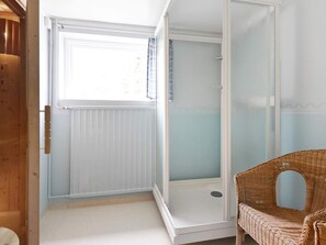A room with a glass door leading to a shower area, a wicker chair, and a window with curtains. - 8 Person Holiday Home in Salen (Salen)