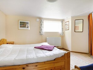 A bedroom with a wooden bed, a window with curtains, a radiator, and a framed picture on the wall. - 8 Person Holiday Home in Salen (Salen)