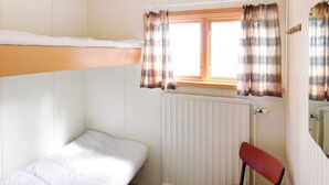 A small, single-room accommodation with a bunk bed, a chair, a table, and a window with curtains. - 8 Person Holiday Home in Salen (Salen)