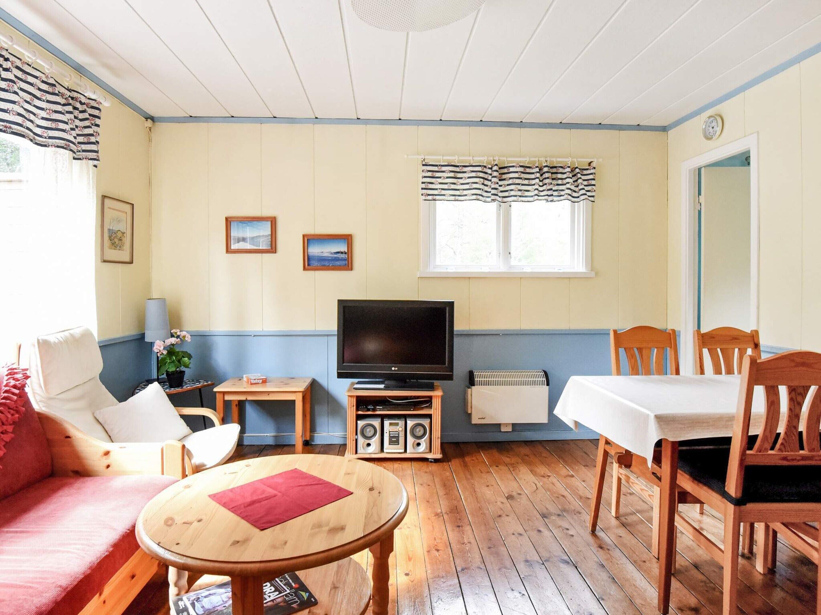 A room with a television, a table, a sofa, and a dining table with chairs.