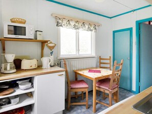 A compact kitchen with a microwave, toaster, kettle, and a small dining table with chairs. - 8 Person Holiday Home in Salen (Salen)