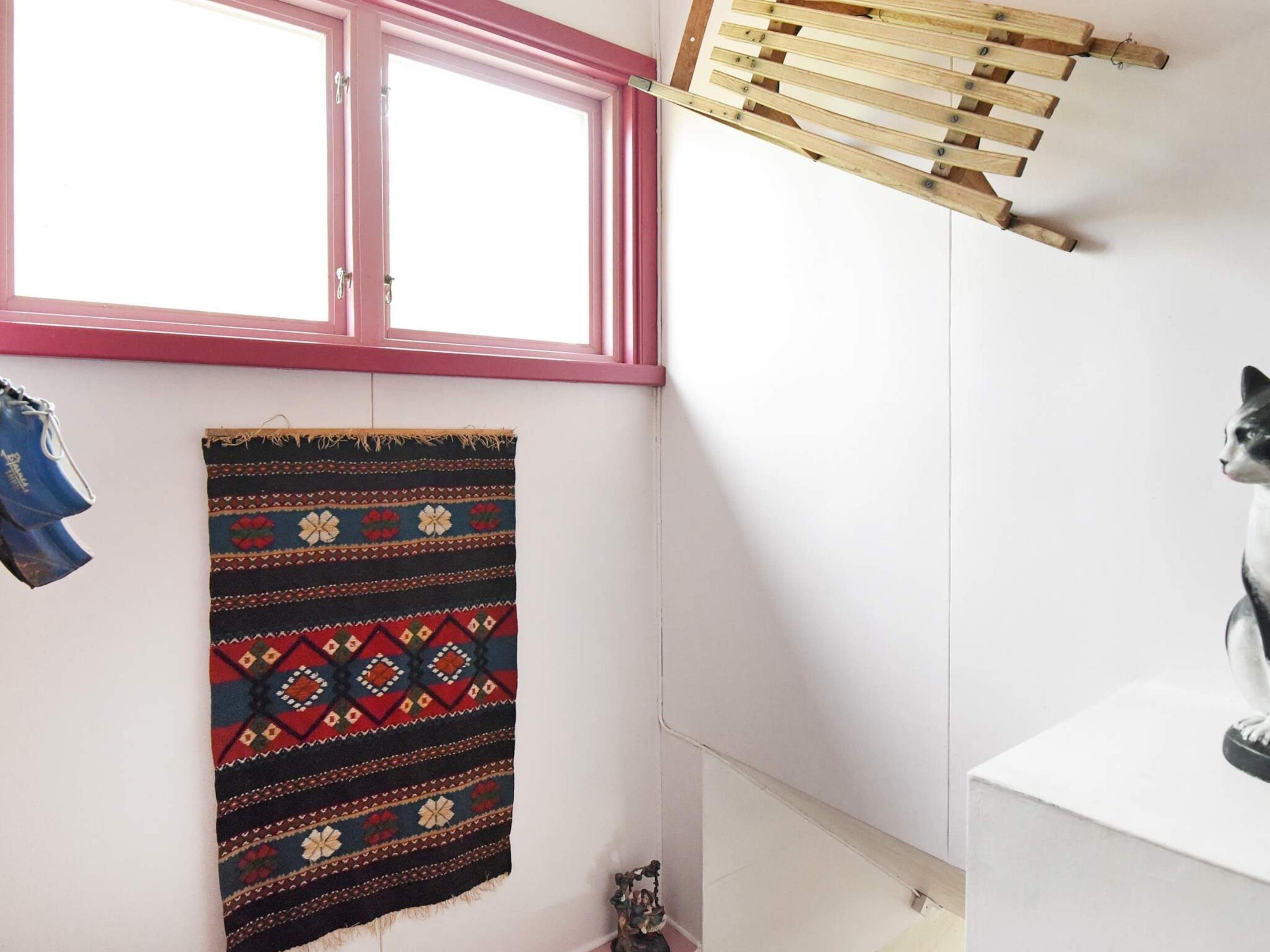 A bathroom with a window, a hanging towel, a drying rack, and a cat statue.