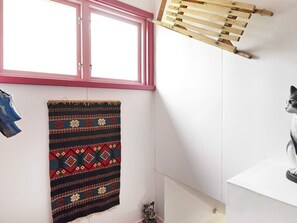 A bathroom with a window, a hanging towel, a drying rack, and a cat statue.