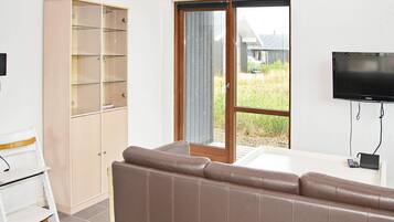 A room with a brown sofa, a wooden cabinet with glass shelves, a sliding glass door, and a mounted television.