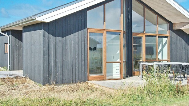 A modern building with a sloped roof, large glass windows, and a wooden exterior. - 8 Person Holiday Home in Ulfborg (Ulfborg)