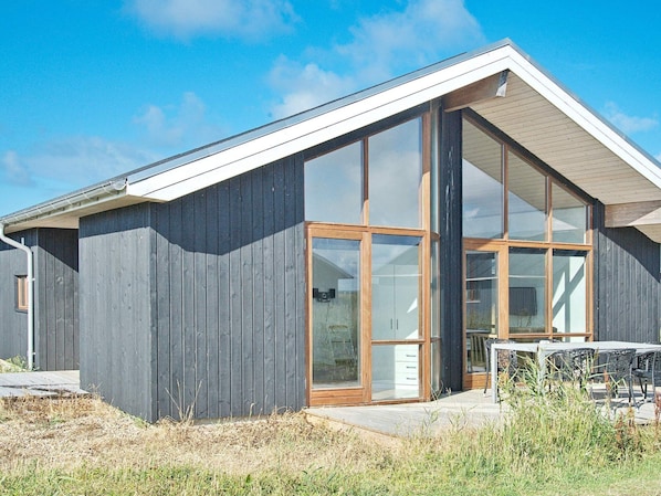 A modern building with a sloped roof, large glass windows, and a wooden exterior.