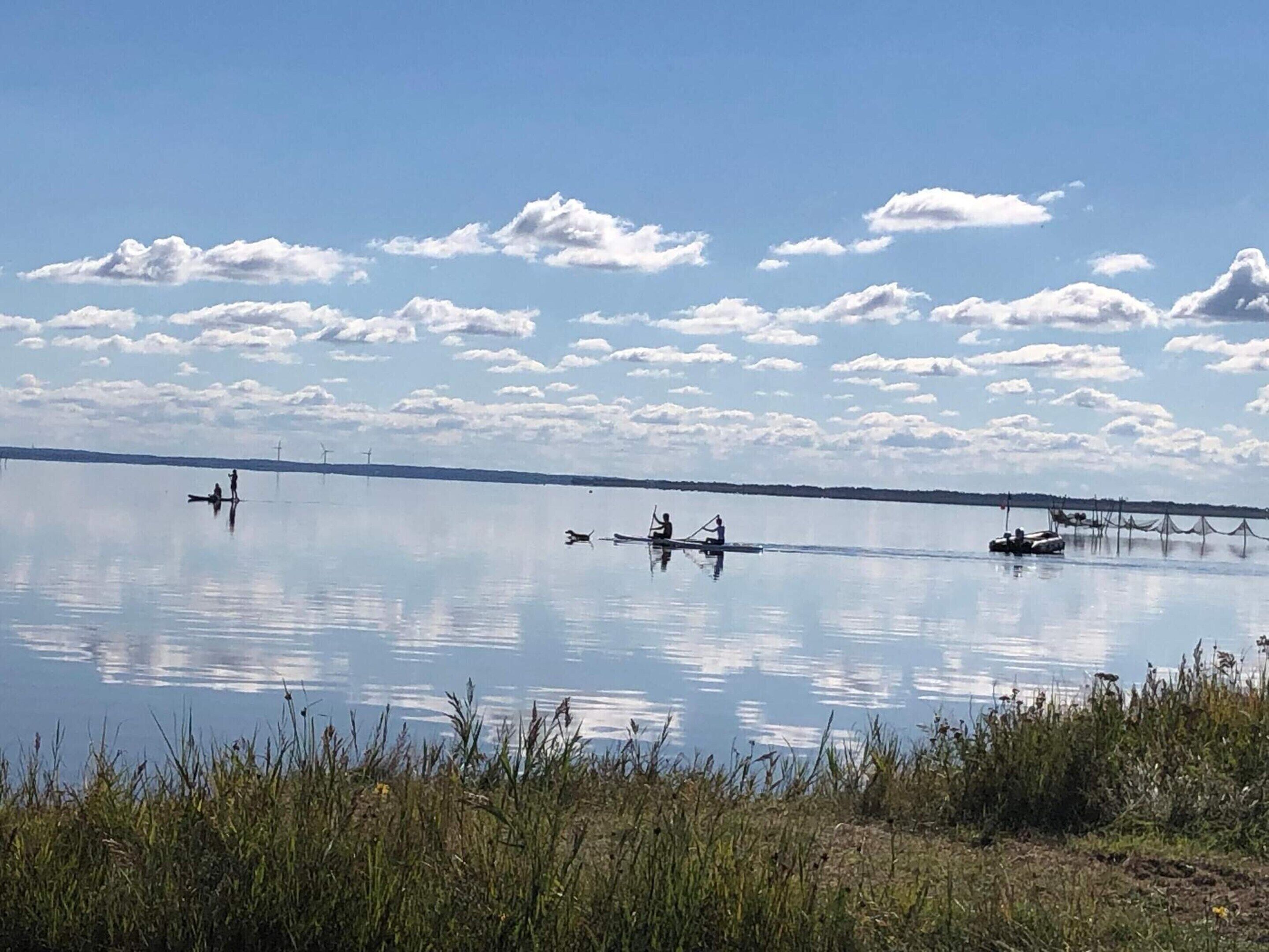 A calm lake with boats and people.