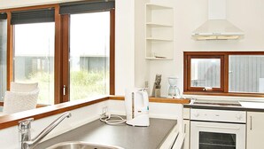 A modern kitchen with a stainless steel sink, white cabinetry, a built-in oven, and a window with a view of the outdoors. - 8 Person Holiday Home in Ulfborg (Ulfborg)