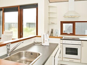 A modern kitchen with a stainless steel sink, white cabinetry, a built-in oven, and a window with a view of the outdoors.