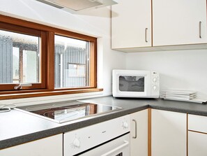 Una cocina con ventana, microondas y pileta.