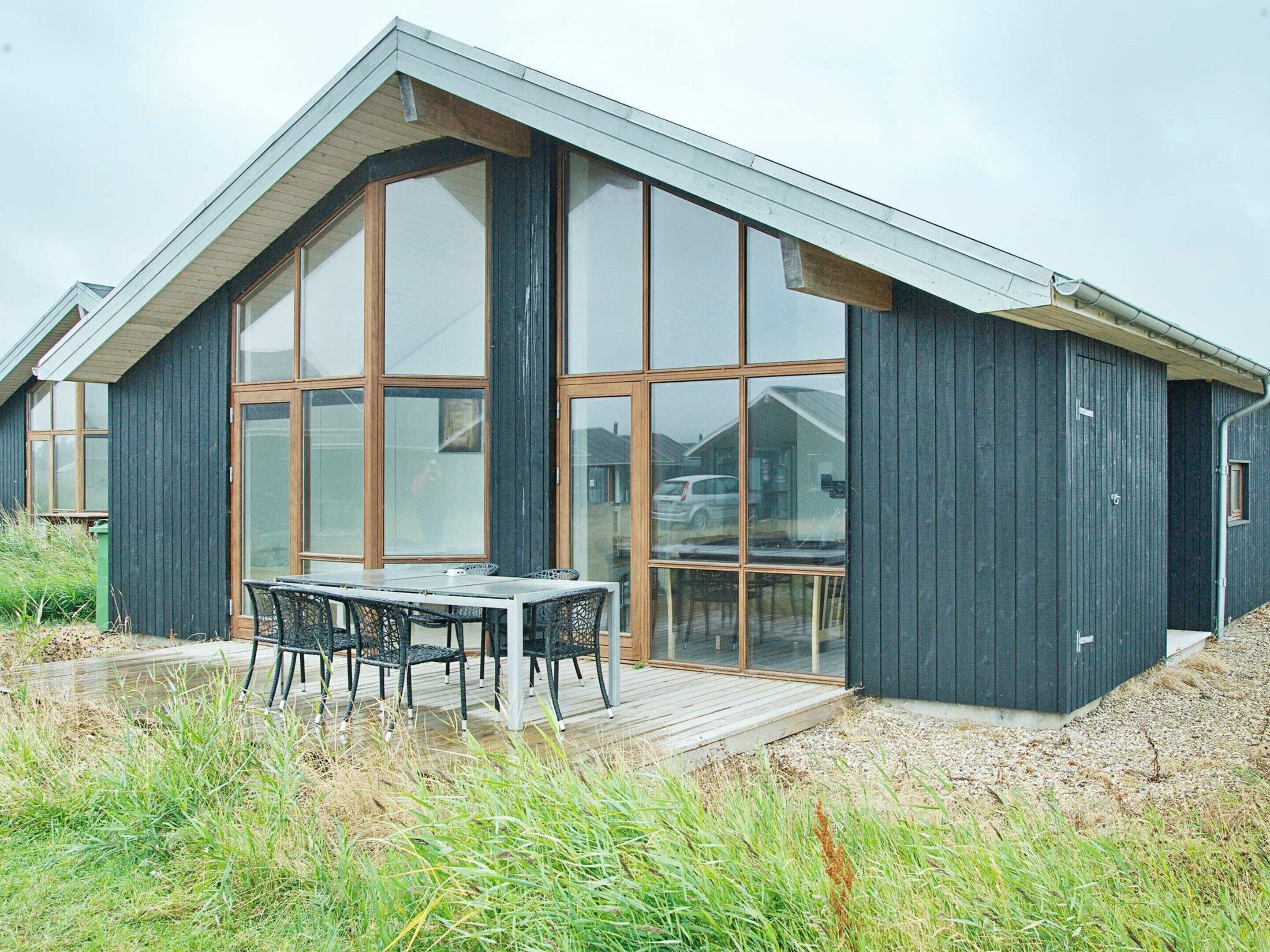 Un bâtiment moderne doté de grandes fenêtres et d’une terrasse en bois.