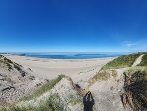 A wide sandy beach with dunes and a clear blue sky. - 8 Person Holiday Home in Ulfborg (Ulfborg)