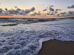 Uma praia com ondas e um pôr do sol.