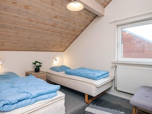 Un dormitorio con dos camas, un tragaluz, un radiador y una ventana.