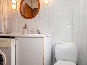 A bathroom with a wooden vanity, a sink, a mirror, a toilet, and a washing machine.