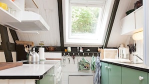 Een kleine keuken met een raam, een waterkoker en een koffiezetapparaat.