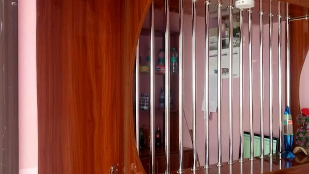 A reception area with a wooden reception desk, a glass partition, and a butterfly decoration on the ceiling. - Charity Lodge (Nakuru)