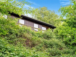 A traditional wooden building surrounded by dense greenery. - Lovely Holiday Home in SpÃ¸ttrup near Sea (Spøttrup)