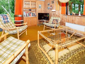 A cozy living room with wicker furniture, a flat-screen TV, and a bookshelf. - Lovely Holiday Home in SpÃ¸ttrup near Sea (Spøttrup)