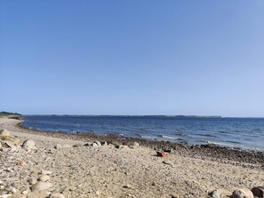 A pebbled beach with a clear sky and calm sea. - Lovely Holiday Home in SpÃ¸ttrup near Sea (Spøttrup)