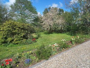 A garden with a variety of flowers and trees, a gravel path, and a grassy area. - 5 Person Holiday Home in Hojer (Højer)