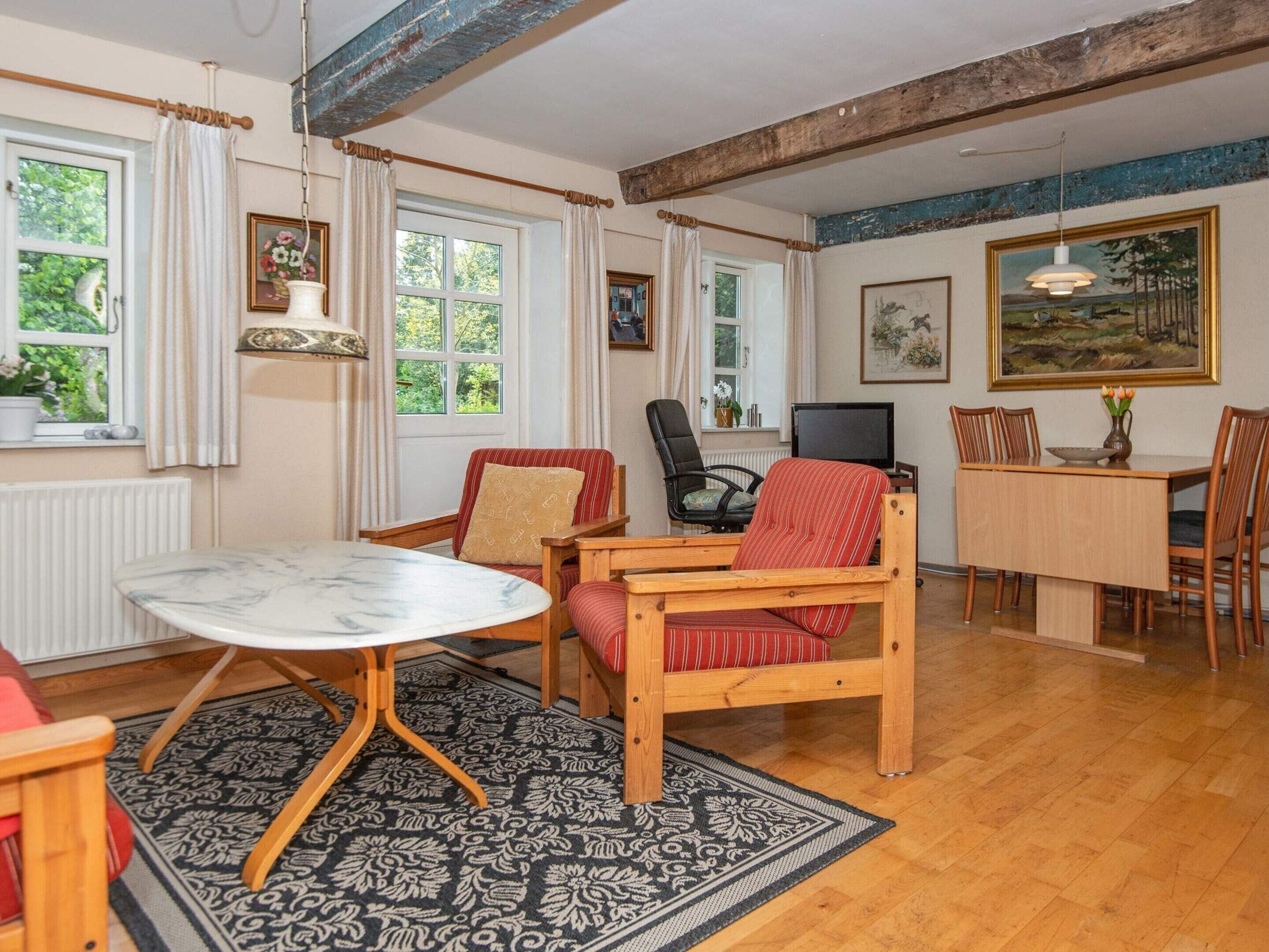 En hyggelig stue med et træbord, en behagelig lænestol, en sofa og et fjernsyn.