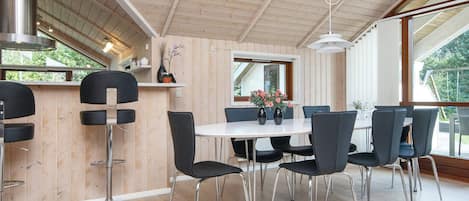 A modern dining area with a wooden ceiling, a white table, and black chairs.