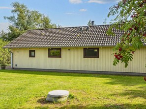 Un bâtiment d’un seul étage, doté d’un toit en tuiles, portant le numéro 52, et comprenant un petit jardin avec un bac à fleurs en béton.