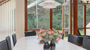 A dining area with a table, chairs, and a vase with flowers.