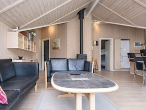A modern interior with a sofa, a table, a fireplace, and a kitchen area.