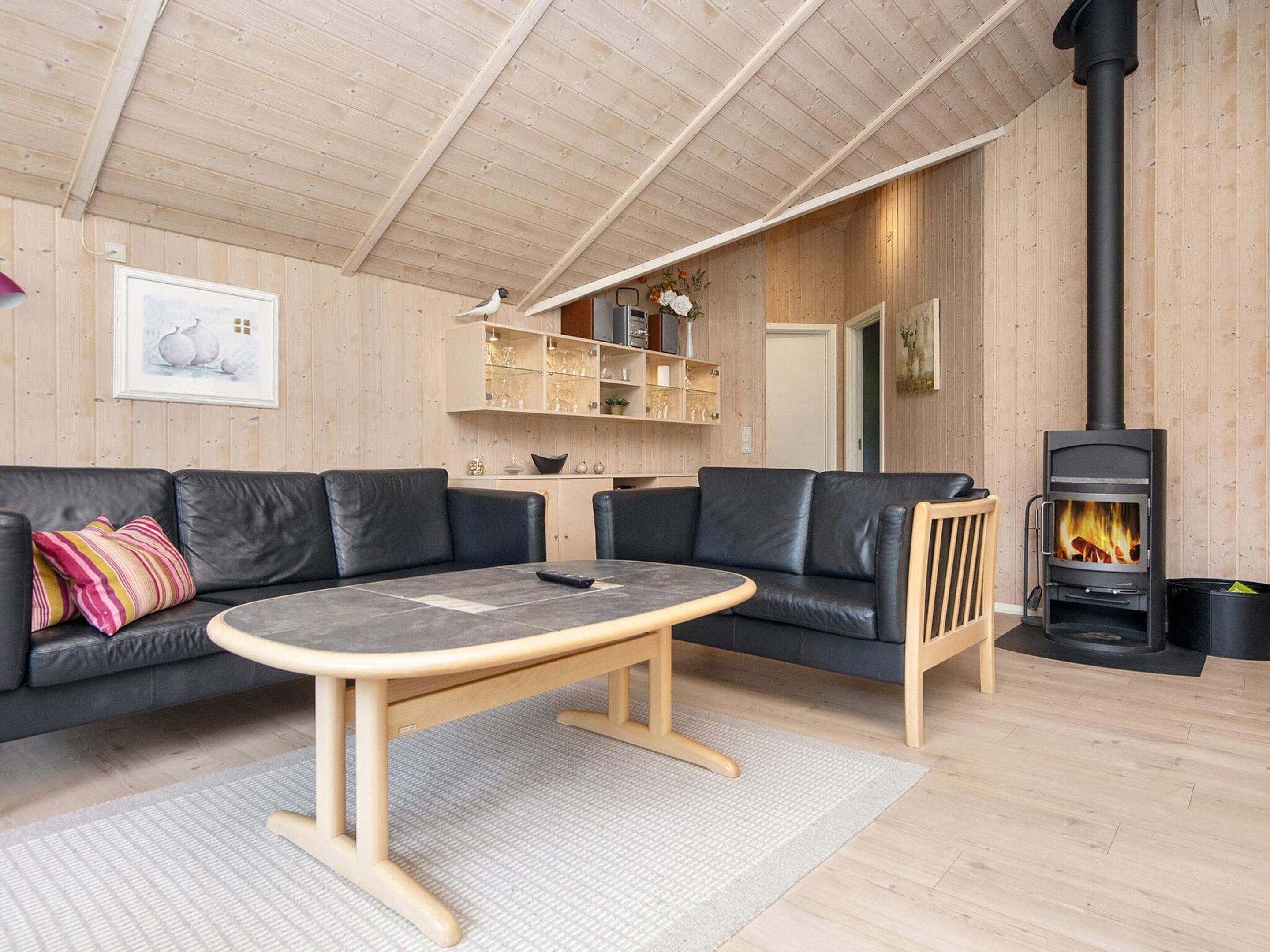 A cozy living room with a sofa, a coffee table, a fireplace, and wooden walls.