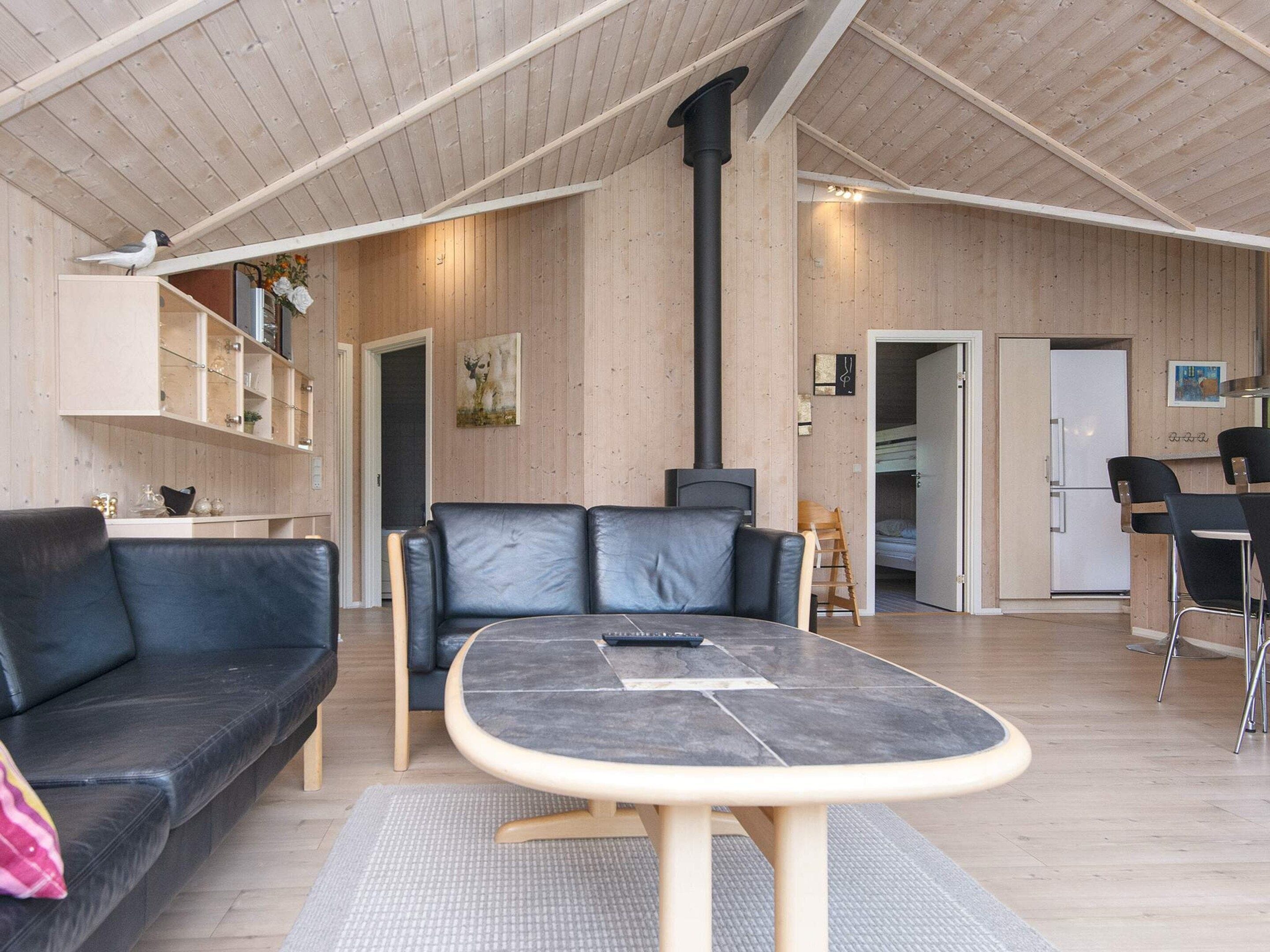 Un interior moderno con un sofá, una mesa, una chimenea y una zona de cocina.