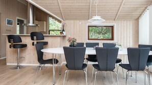 Un interior moderno con comedor, cocina y ventanas amplias.