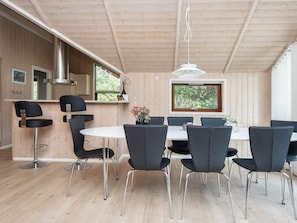A modern interior with a dining area, kitchen, and large windows.