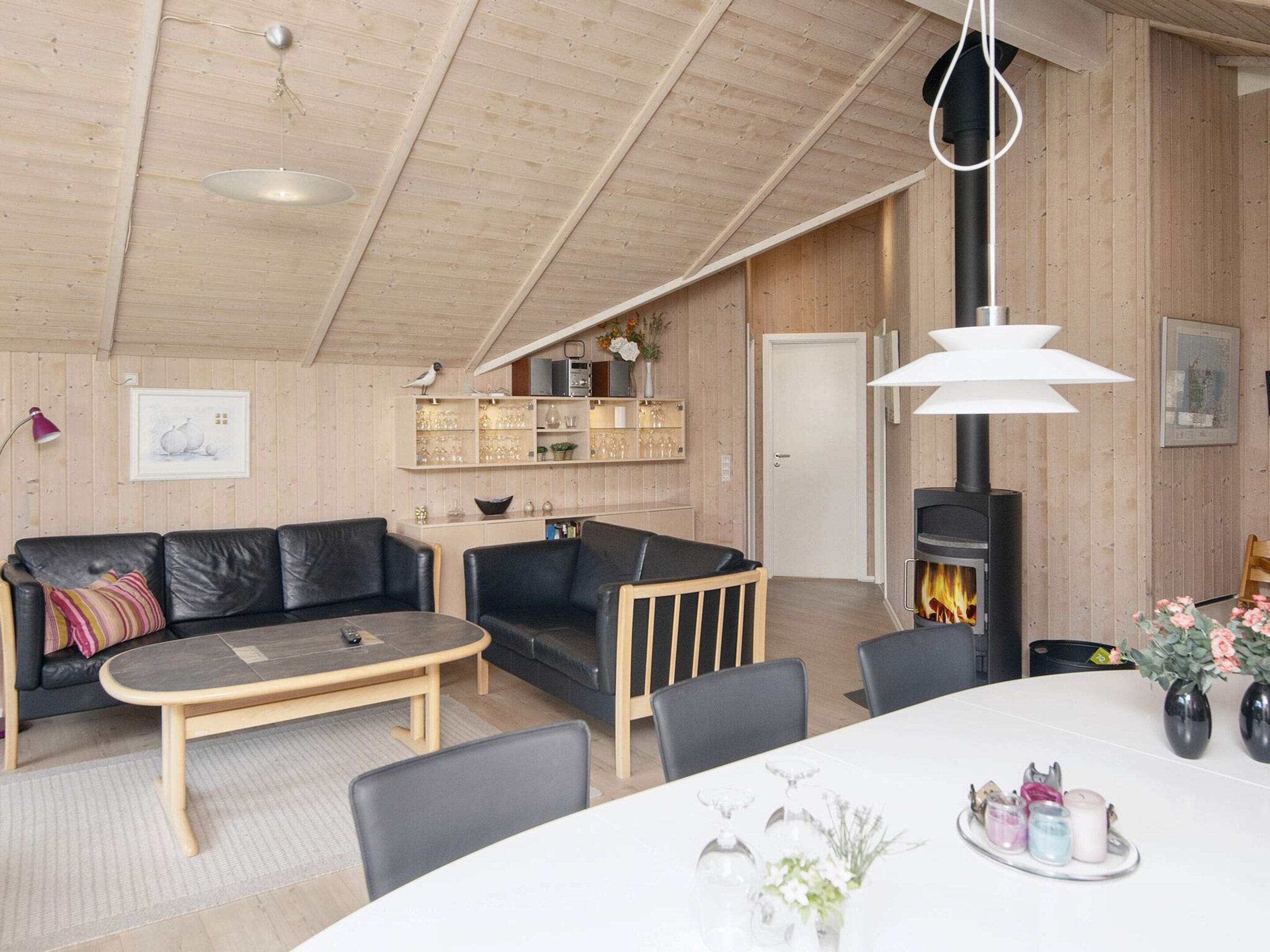 Una sala de estar acogedora con chimenea, paredes de madera, un sofá, una mesa de centro y un comedor.