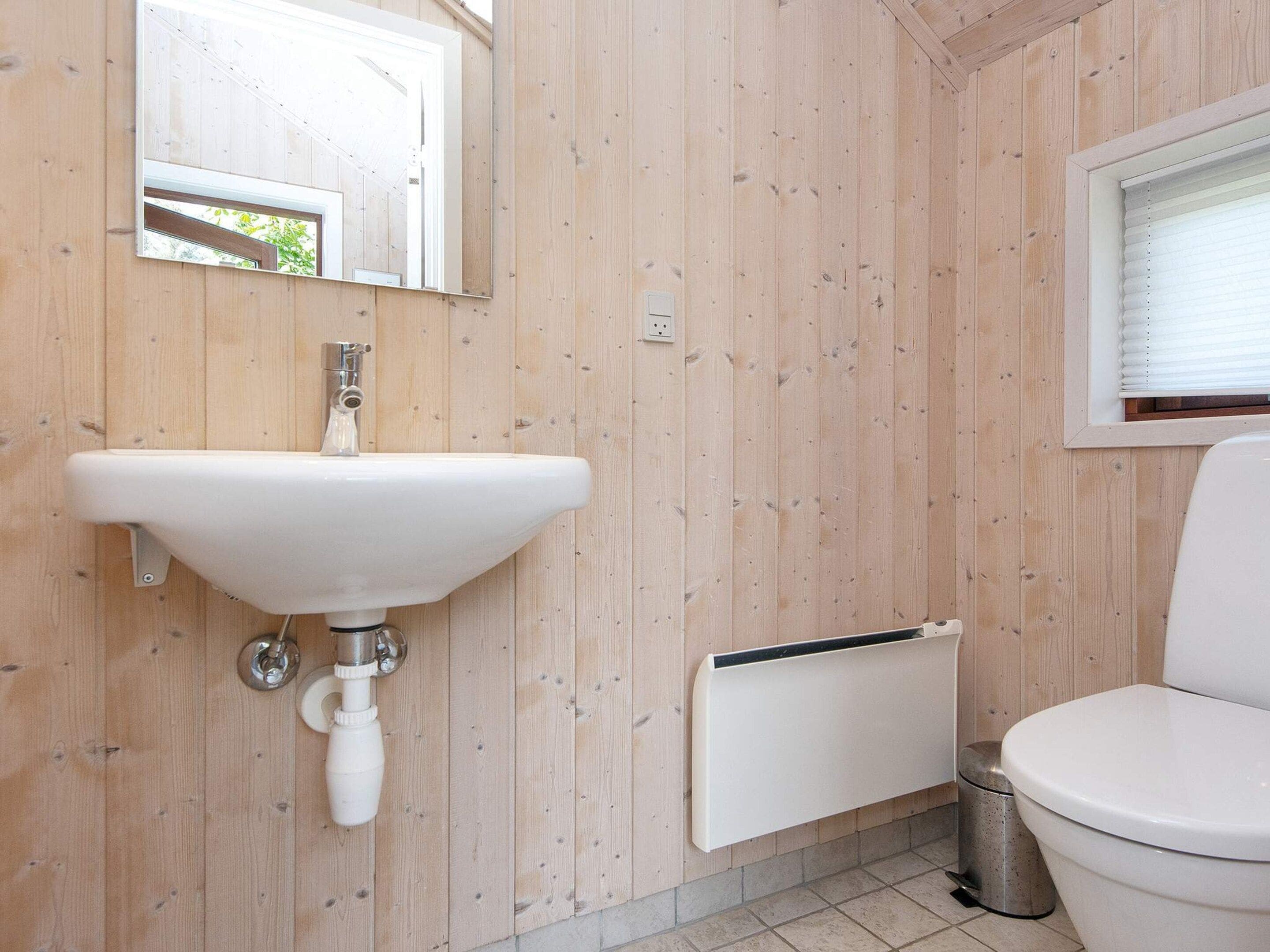 A bathroom with a white sink, a toilet, and a window with blinds.