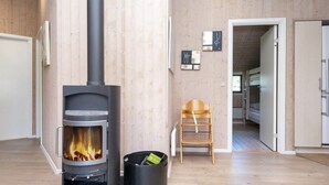Una habitación con estufa de leña, una silla y una puerta que da a otra estancia.