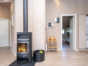 A room with a wood-burning stove, a chair, and a door leading to another room.