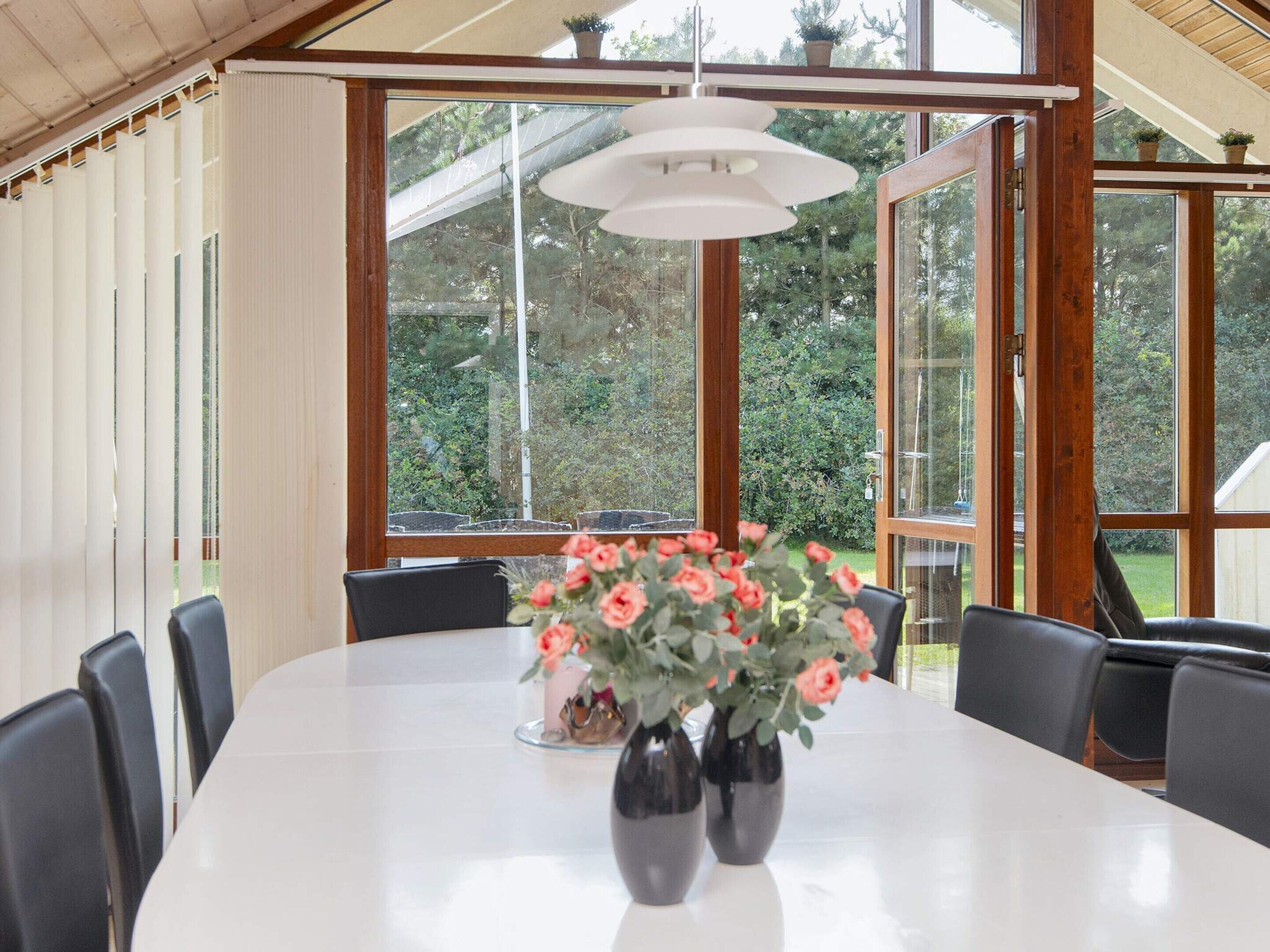 A dining area with a table, chairs, and a vase with flowers.
