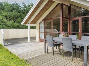 A covered patio with a table and chairs, a wooden deck, and a view of the surrounding greenery. - 5 Star Holiday Home in Ulfborg (Ulfborg)