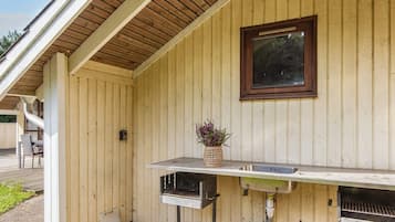 An outdoor kitchen area with a grill, a sink, and a window.